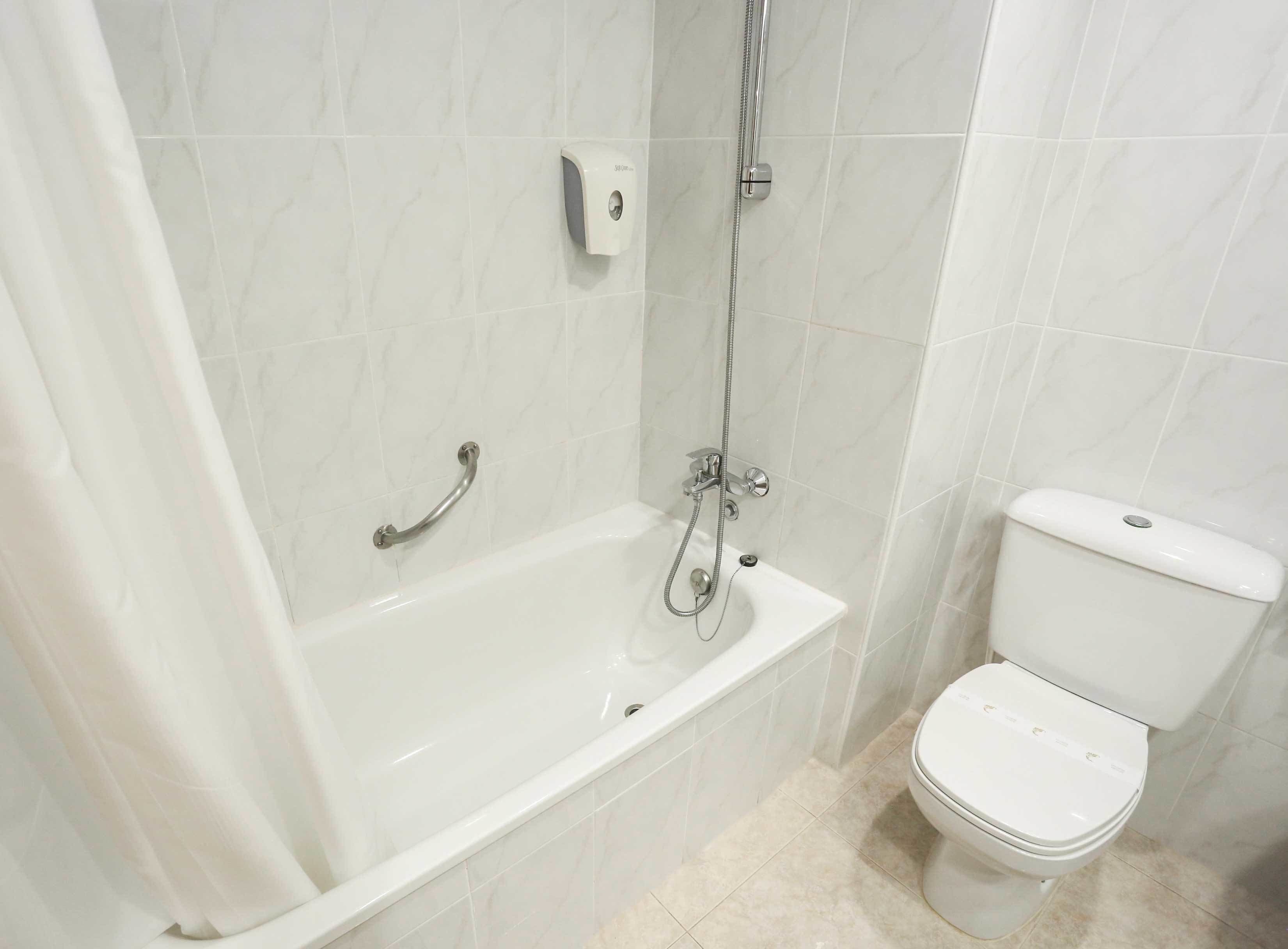 Baño con bañera, inodoro y secamanos.