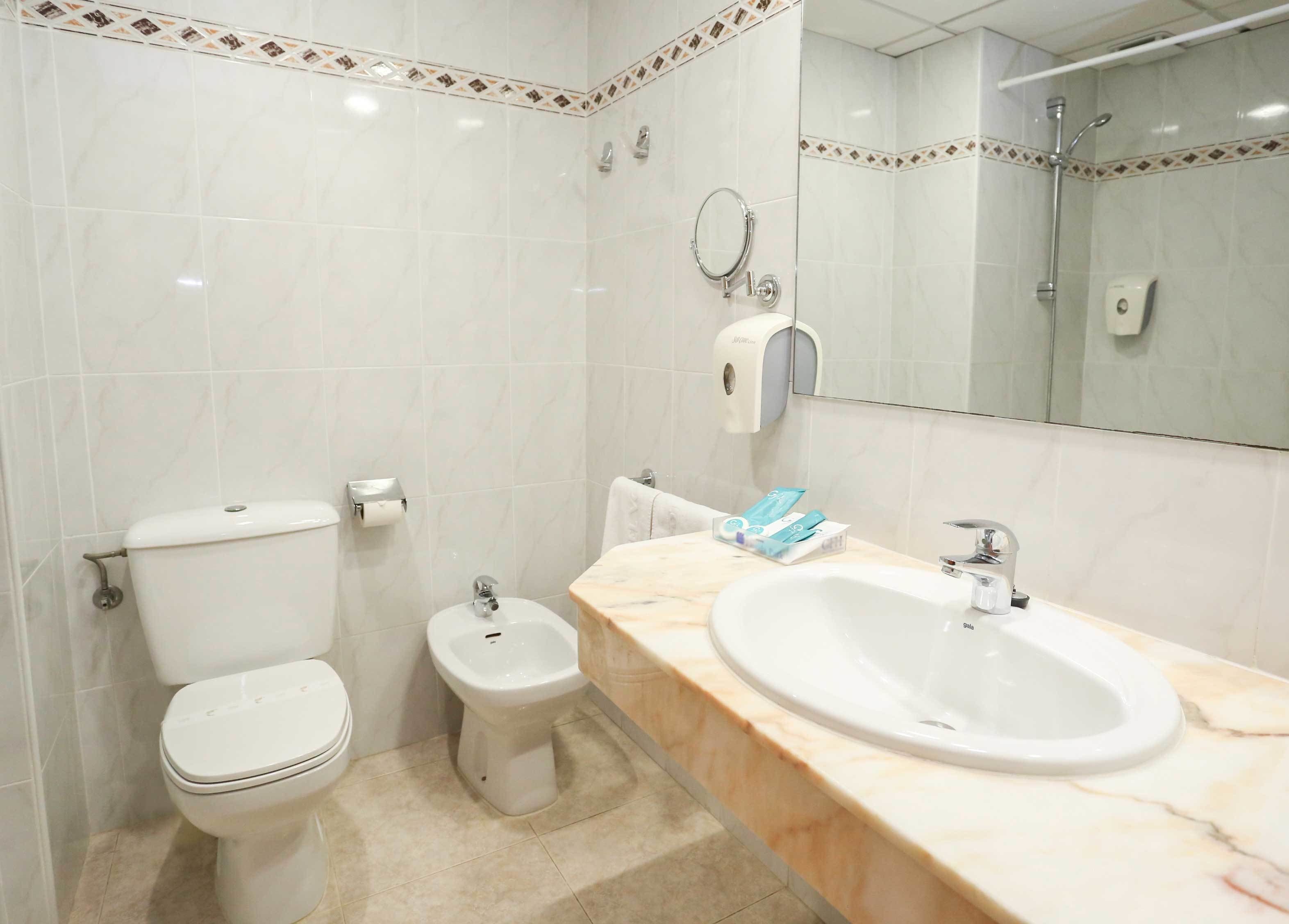 A modern bathroom with a toilet, bidet, and a sink with a mirror.