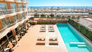 A rooftop pool area with sun loungers and umbrellas, overlooking a beach and ocean. - KAKTUS Hotel Volga (Calella)