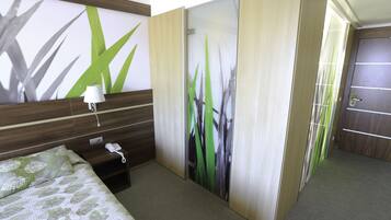 Une chambre d’hôtel avec un lit, une table de chevet avec un téléphone et un mur orné d’un motif de feuilles.