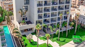 Un hôtel moderne doté de nombreux balcons, d’une piscine et d’un jardin bien entretenu.