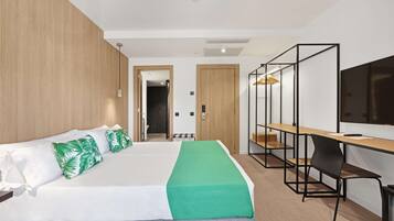 A modern hotel room with a large bed, a desk, and a TV.