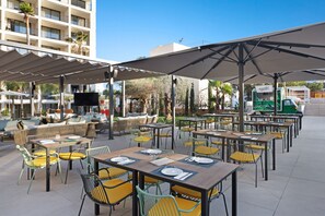 An outdoor dining area with tables and chairs, a covered seating area, and a building in the background. - Paradiso Garden Hotel (Palma de Mallorca)