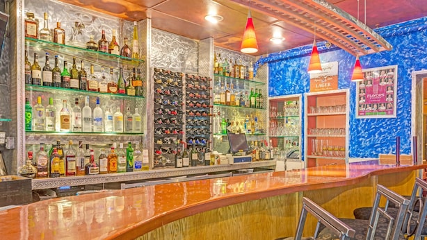 A bar with shelves of liquor bottles, a counter, and bar stools.
