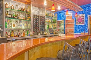 Un bar amb amples prestatges plens de garrafes de licors, una barra i tamborets.