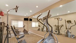A gym with various exercise equipment, including a treadmill, elliptical, and weight machines.
