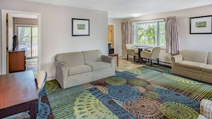 A living room with a patterned carpet, two sofas, a dining table, and chairs. - Travelodge by Wyndham Great Barrington Berkshires (Great Barrington)