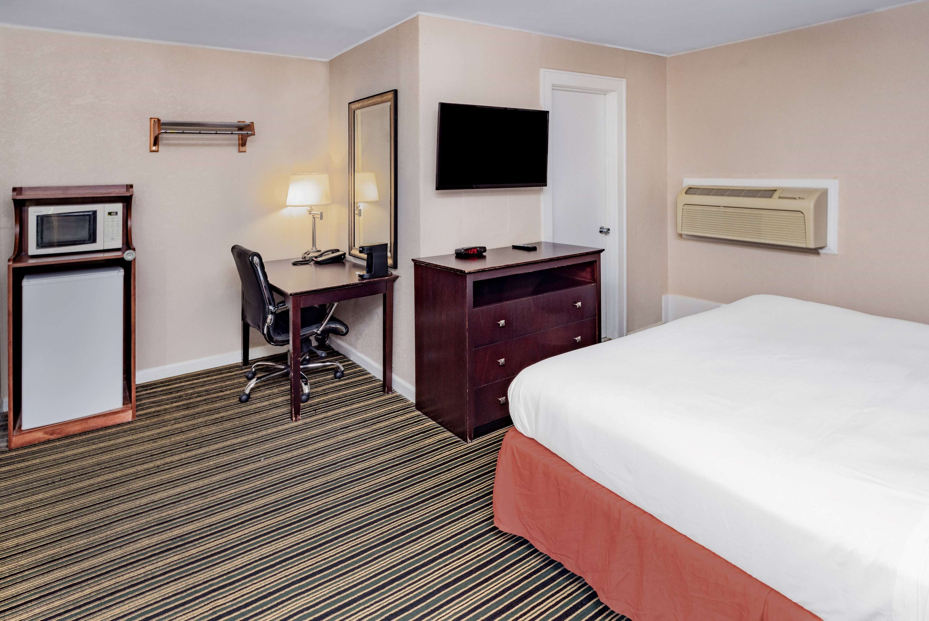 Habitación de hotel con cama, escritorio y silla, televisor, microondas y calefacción.