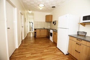 Eine Küche mit Holzboden, weißen Schränken, einem Kühlschrank und einer Mikrowelle.