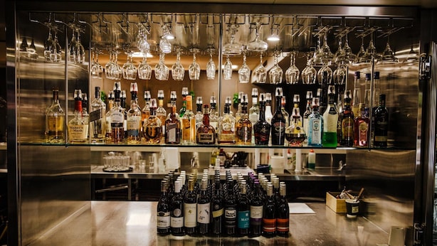A bar area with numerous bottles of alcohol and hanging wine glasses. - Kalgoorlie Overland Motel (Somerville)