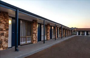 A row of motel rooms with stone pillars and large windows. - Kalgoorlie Overland Motel (Somerville)