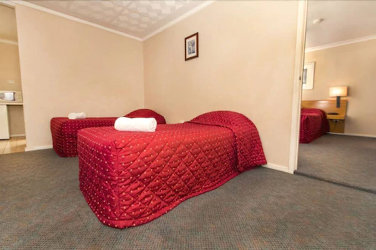 Habitación de hotel con dos camas, una mesita y una silla.