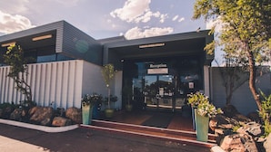 A modern building with a reception area, large windows, and potted plants. - Kalgoorlie Overland Motel (Somerville)