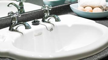 A white sink with two chrome faucets and a soap dish.