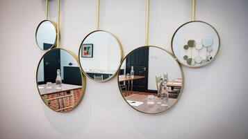 A room with a table and chairs, a mirror, and a wall-mounted light fixture.