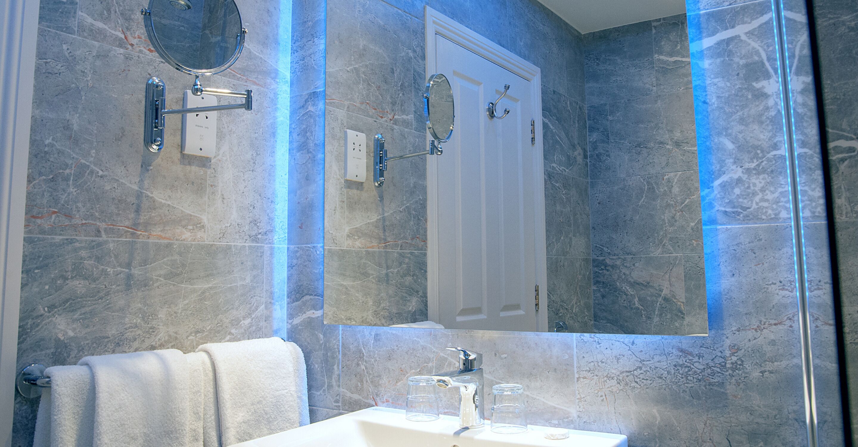 A bathroom with a white sink, a mirror, and a towel rack.