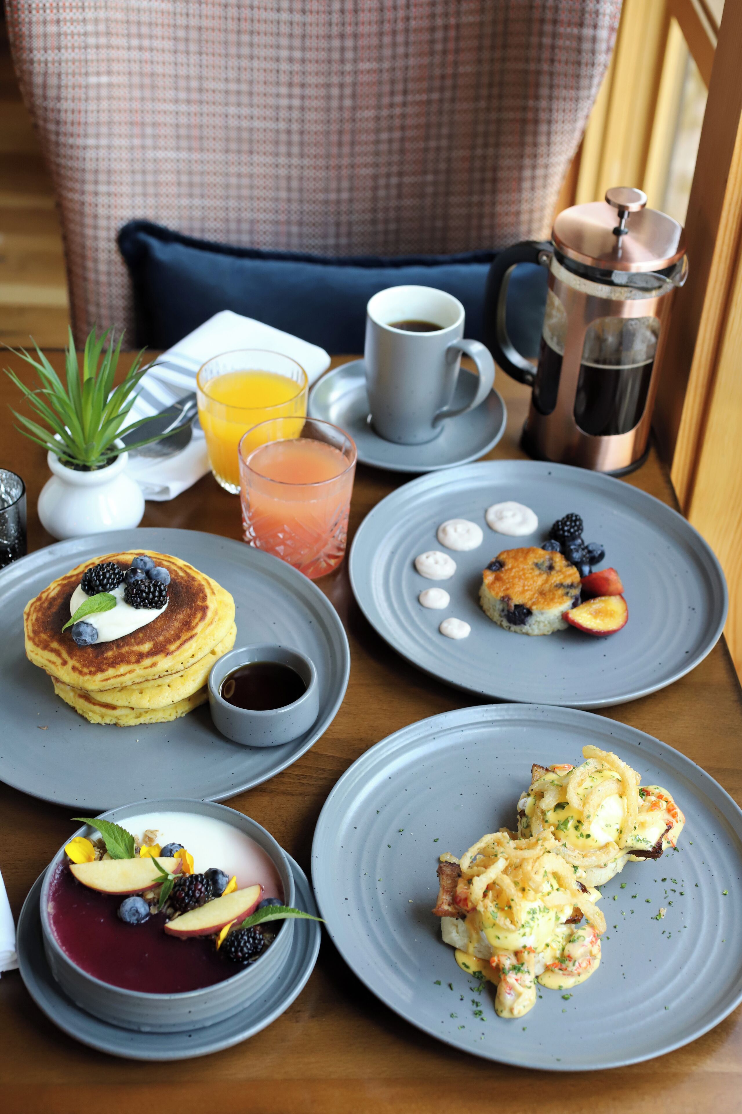 Una mesa de desayuno con panqueques, scones y un postre de bayas.