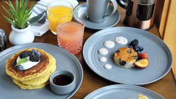 Una mesa de desayuno con panqueques, scones y un postre de bayas.