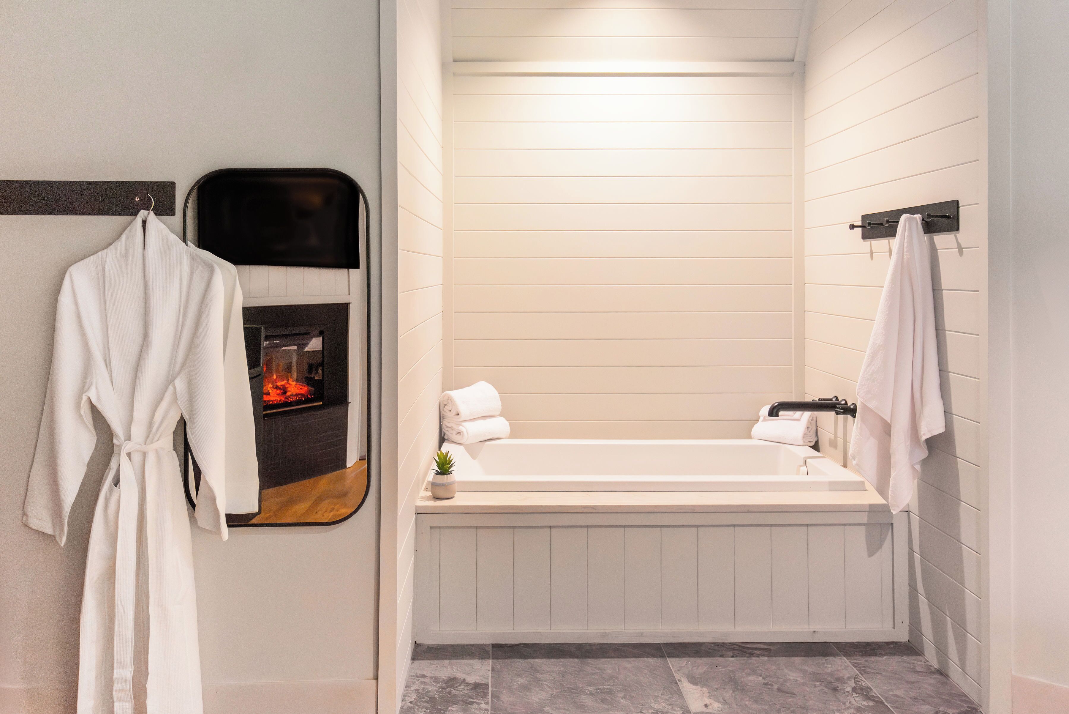 A modern bathroom with a bathtub, a mirror, and a towel rack.