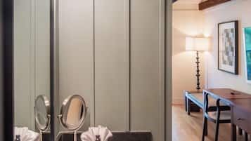 Une salle de bain avec un lavabo blanc, deux miroirs et un meuble-lavabo. On y trouve également un banc en bois et une table dans la pièce adjacente.