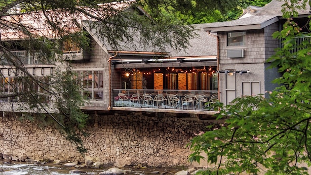 Un restaurant situé au bord de la rivière, doté d’une terrasse, de murs en pierre et offrant une vue sur le fleuve.