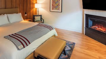 Habitación de hotel con cama, banca, chimenea, televisión y lámpara.