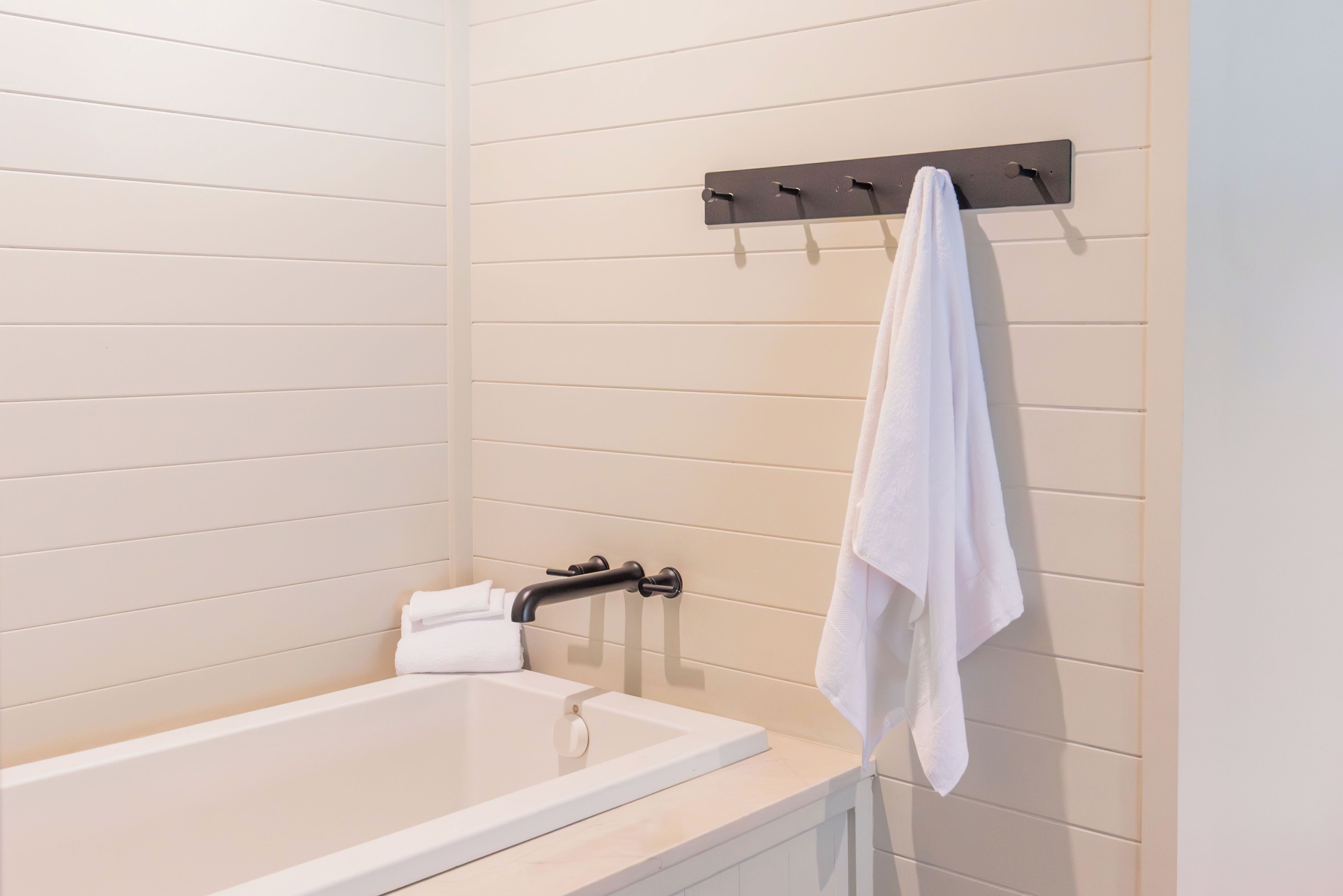 A modern bathroom with a bathtub, a towel rack, and a towel hanging on the wall.