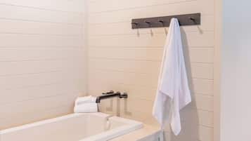 A modern bathroom with a bathtub, a towel rack, and a towel hanging on the wall.
