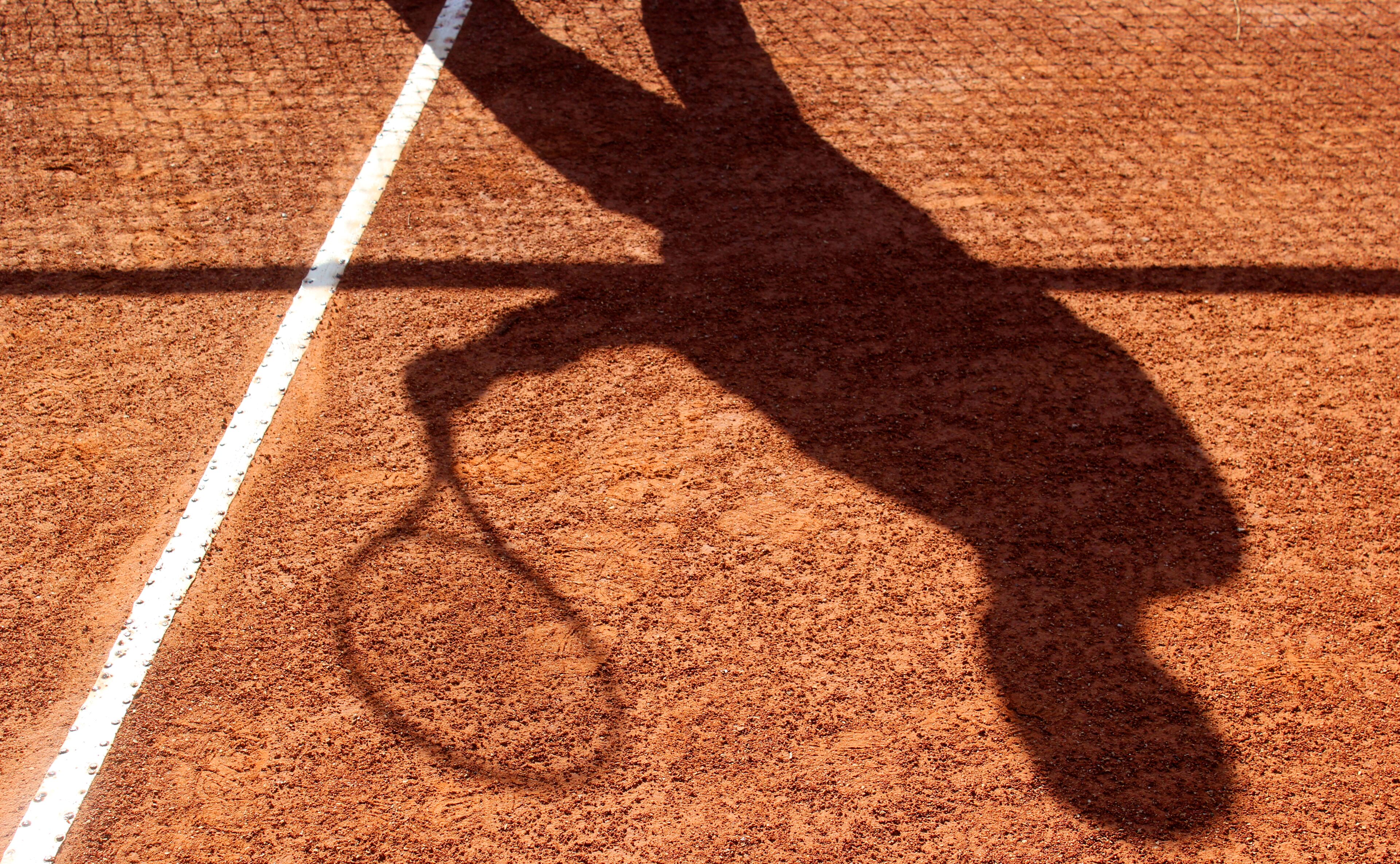 Ein Tennisplatz mit dem Schatten eines Tennisspielers.