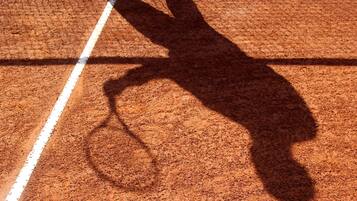 Una cancha de tenis con la sombra de un jugador.