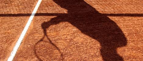 Ein Tennisplatz mit dem Schatten eines Tennisspielers.