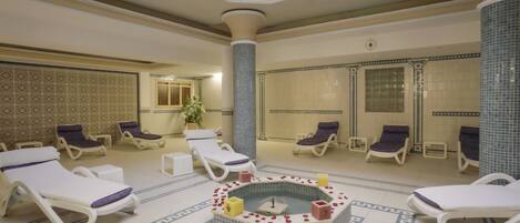 A spa area with multiple sun loungers, a central hot tub, and decorative tiles.