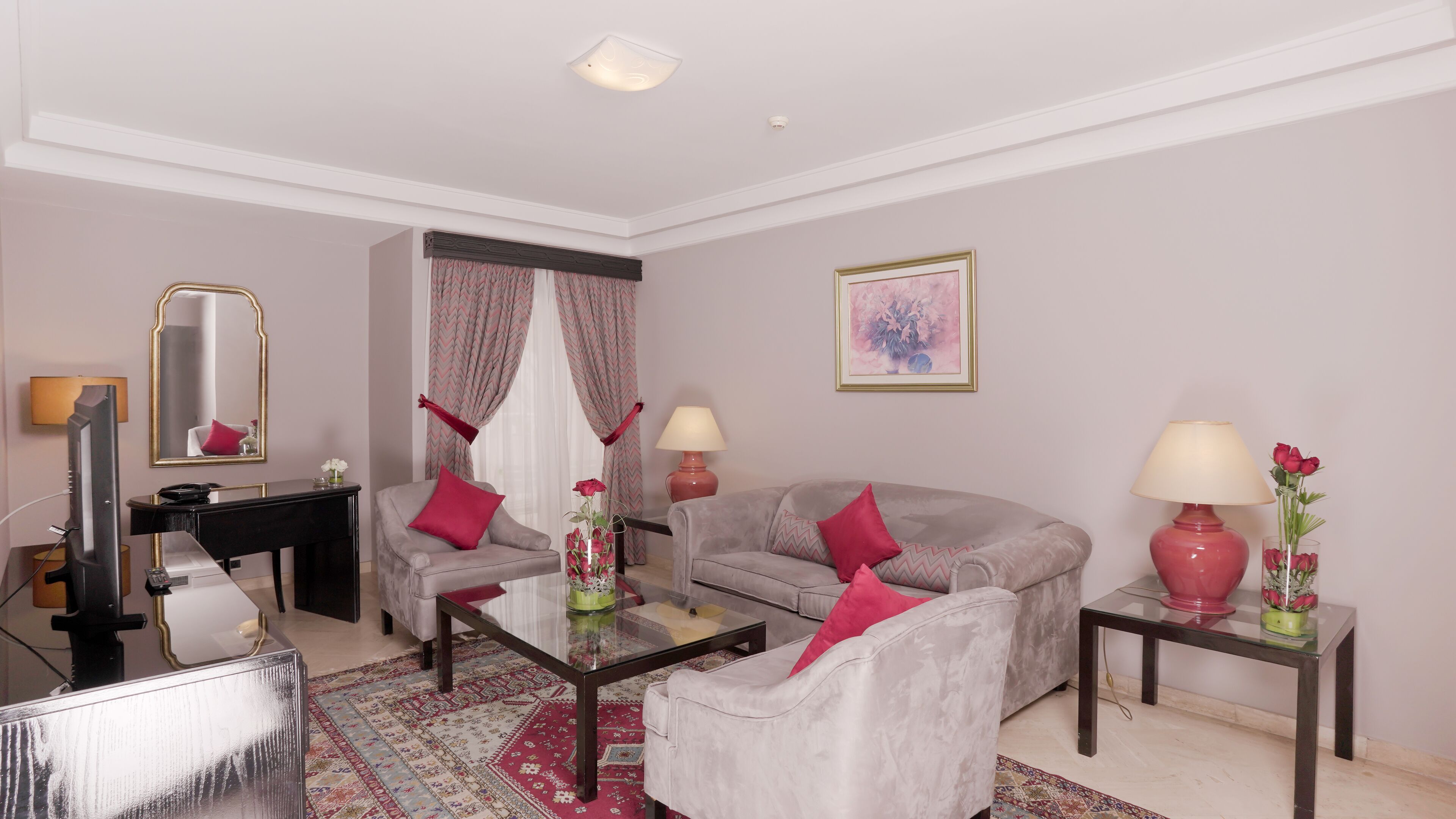A living room with a sofa, armchairs, a coffee table, a TV, and two lamps.