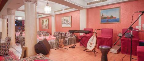 Una habitación con un piano, un instrumento de cuerda y una batería, que sugiere un salón de música o un espacio para practicar.
