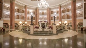 A grand lobby with a central fountain, multiple floors, and a chandelier. - AGADIR BEACH CLUB HOTEL (Agadir)