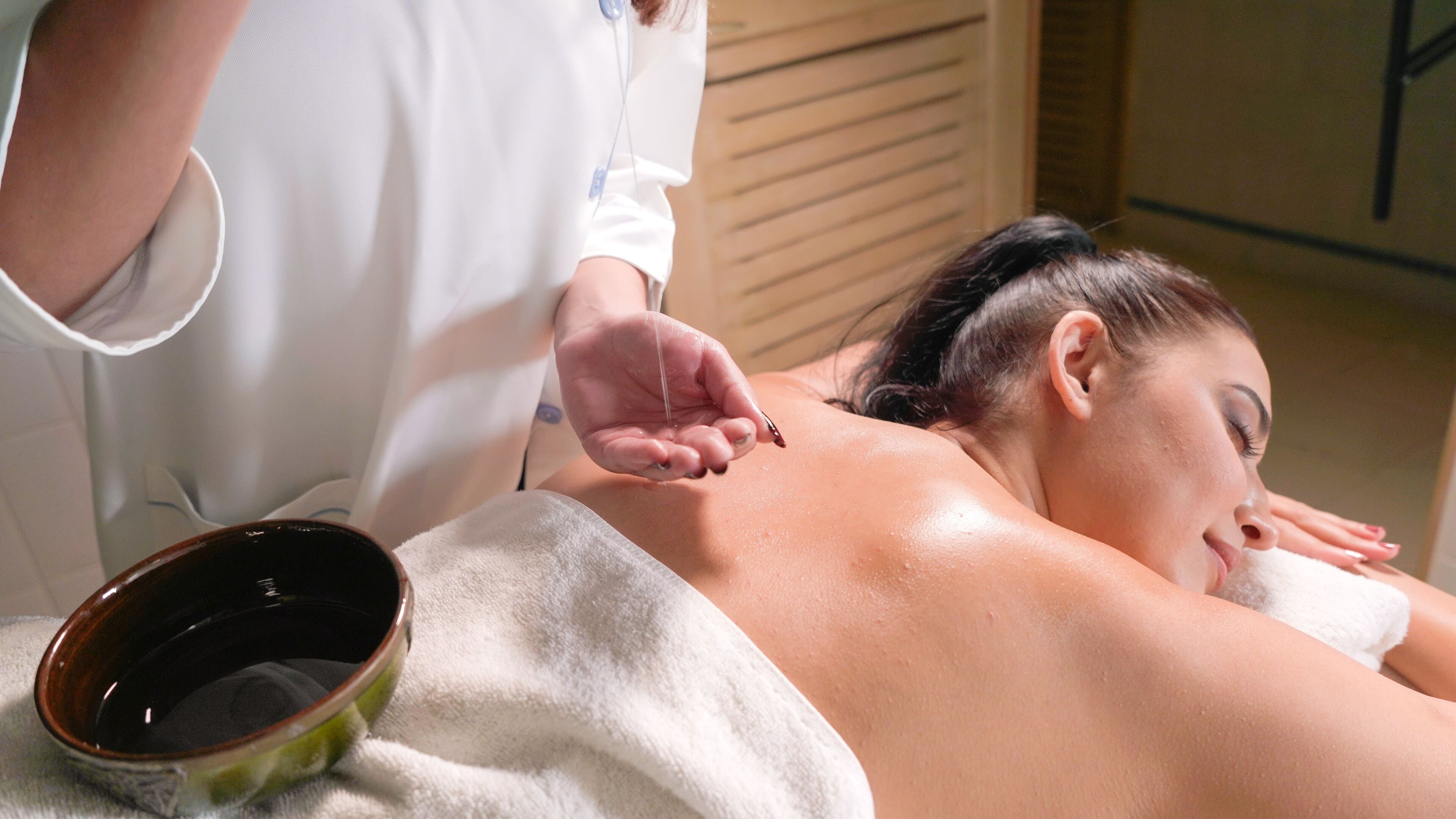 A person receiving a treatment with a hand applying a substance to their back.