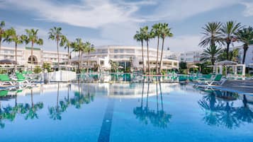 Una piscina al aire libre, sombrillas, sillones reclinables de piscina