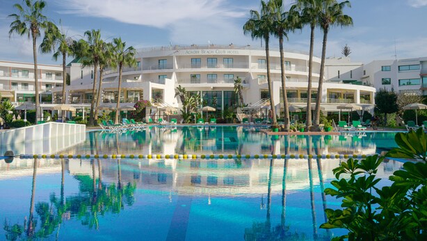 A hotel with a large pool surrounded by palm trees and lounge chairs. - AGADIR BEACH CLUB HOTEL (Agadir)