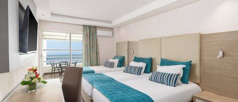 A hotel room with two beds, a desk, a chair, a TV, and a balcony with a view.