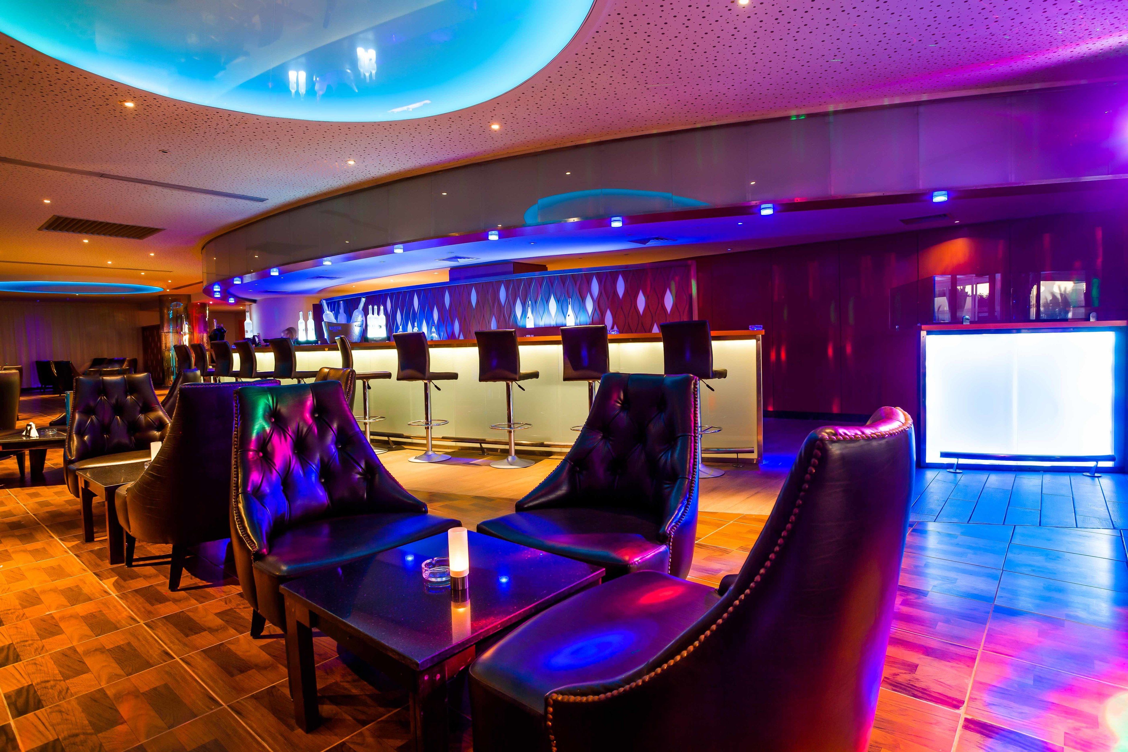A modern bar area with leather seating and a bar counter.