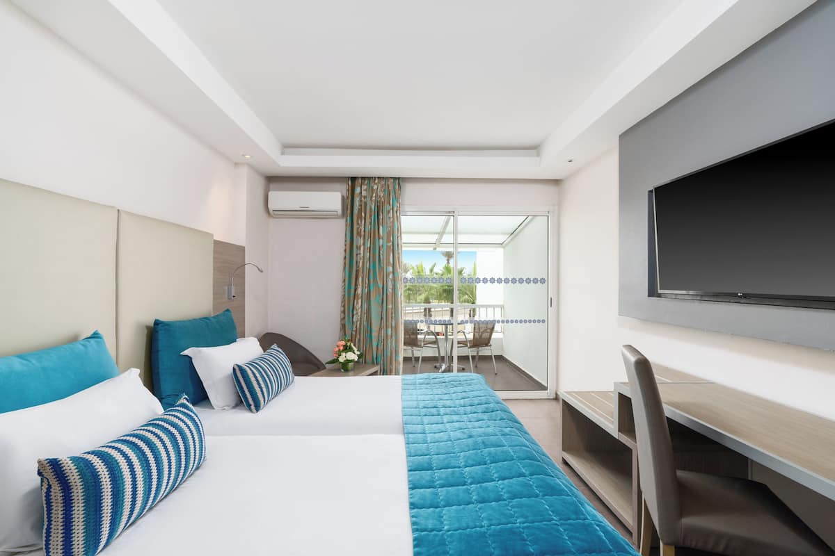 A hotel room with a bed, a desk, and a TV.