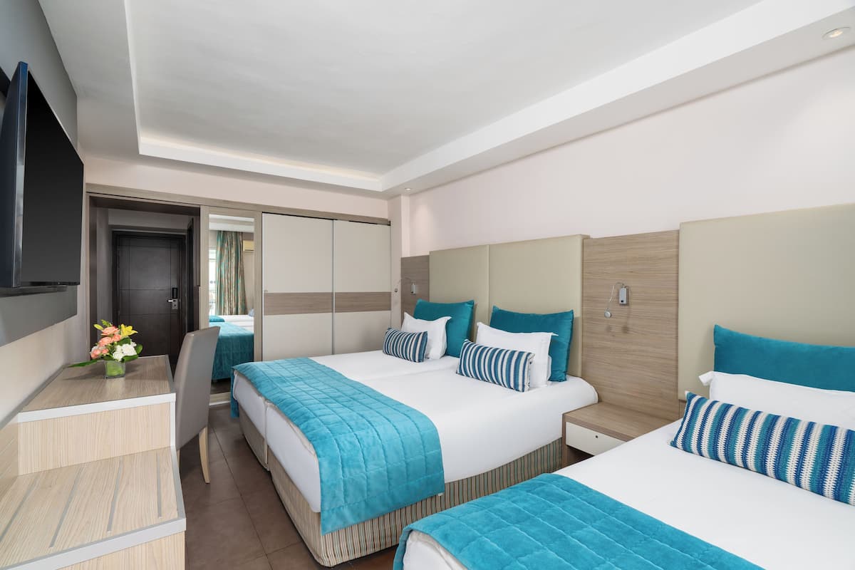 A hotel room with two beds, a desk, and a TV.