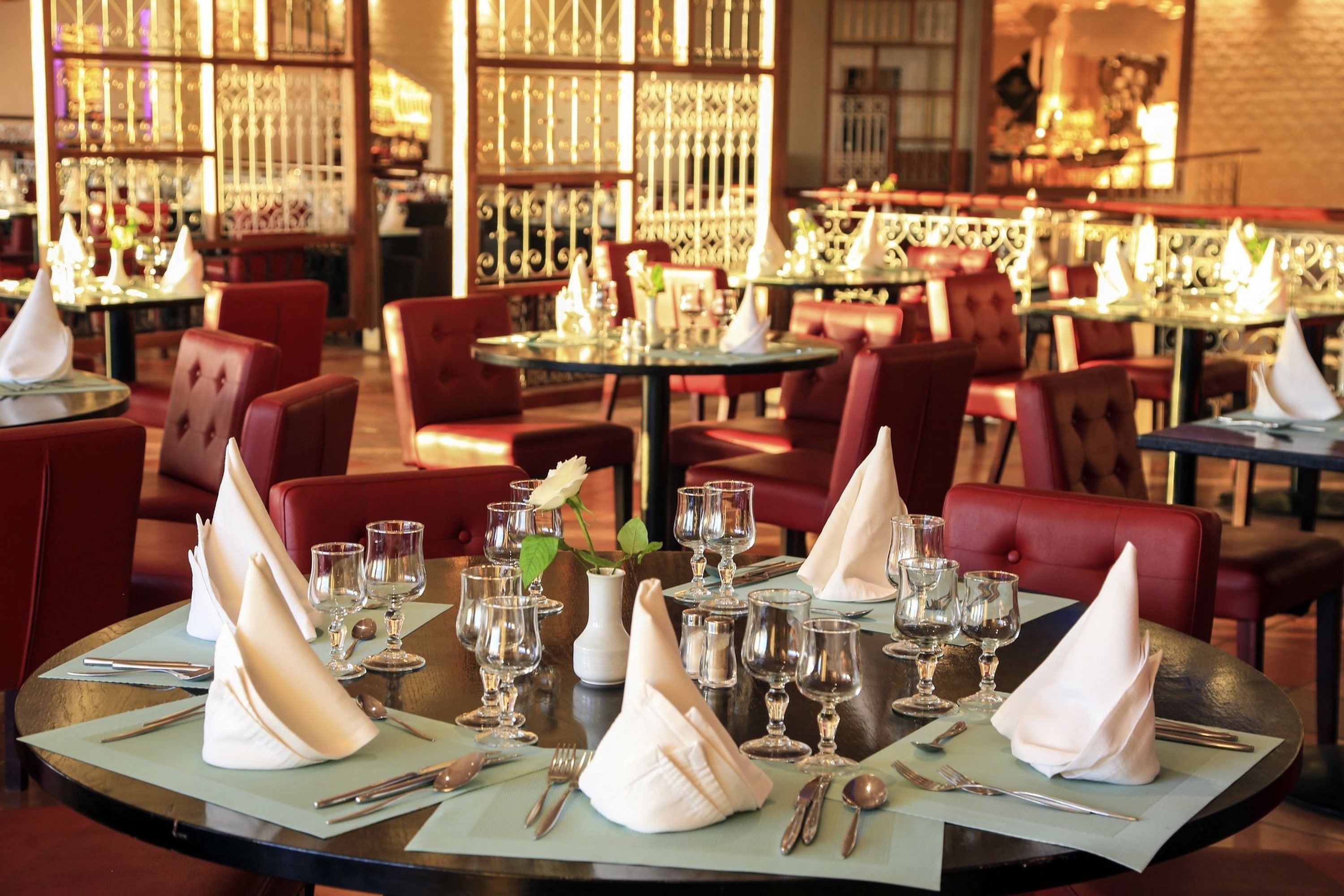 A restaurant with round tables set for dining, featuring neatly folded napkins and wine glasses.