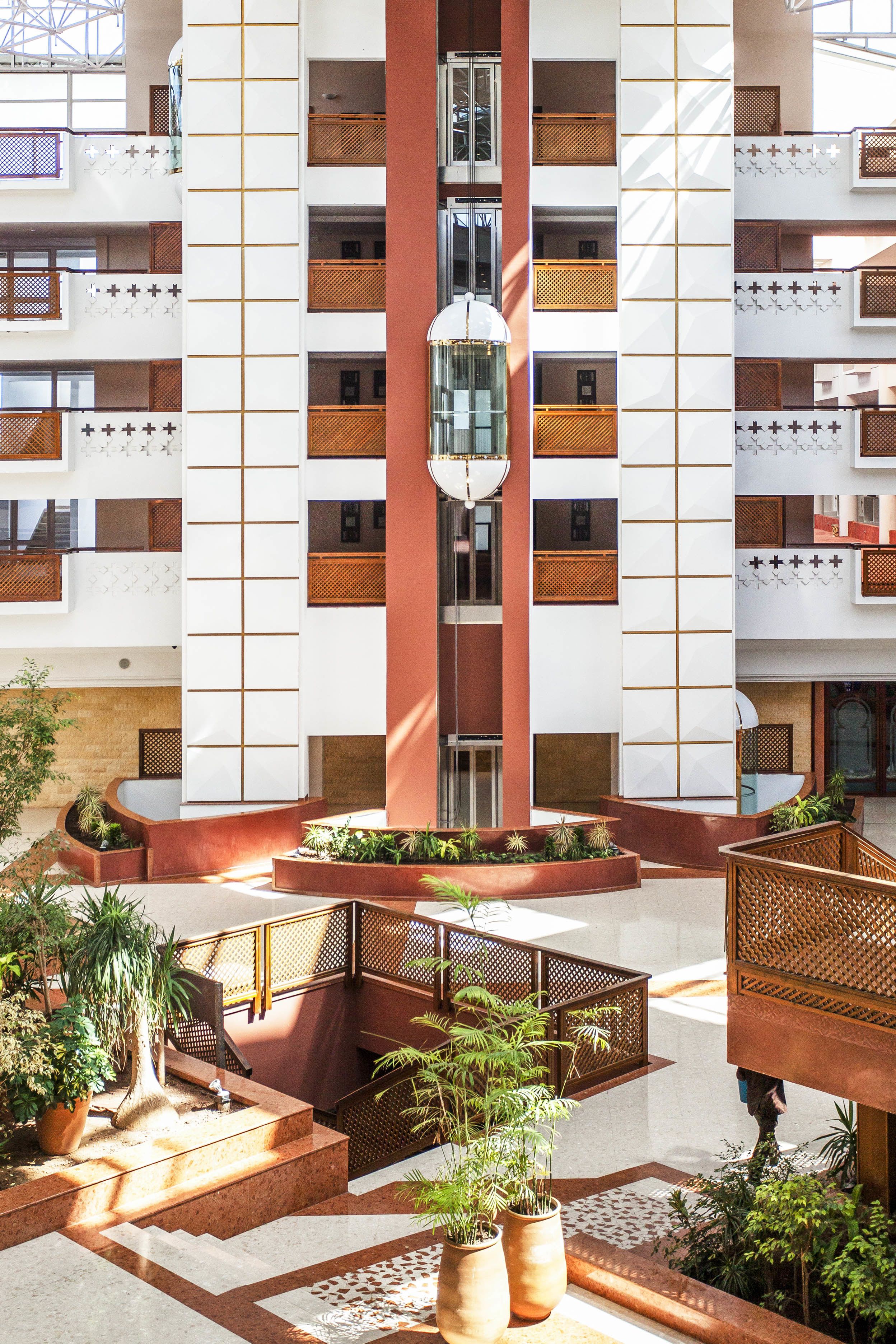 Ein mehrstöckiges Hotel mit einem zentralen Atrium, Balkonen und Außenpflanzenarrangements.