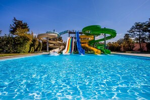 A swimming pool with multiple water slides, including a rainbow-colored slide and a green spiral slide. - Amadil Ocean Club (Agadir)