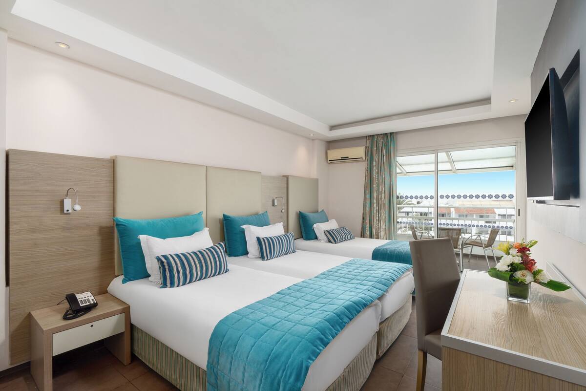A hotel room with two beds, a desk, a chair, a phone, and a TV.