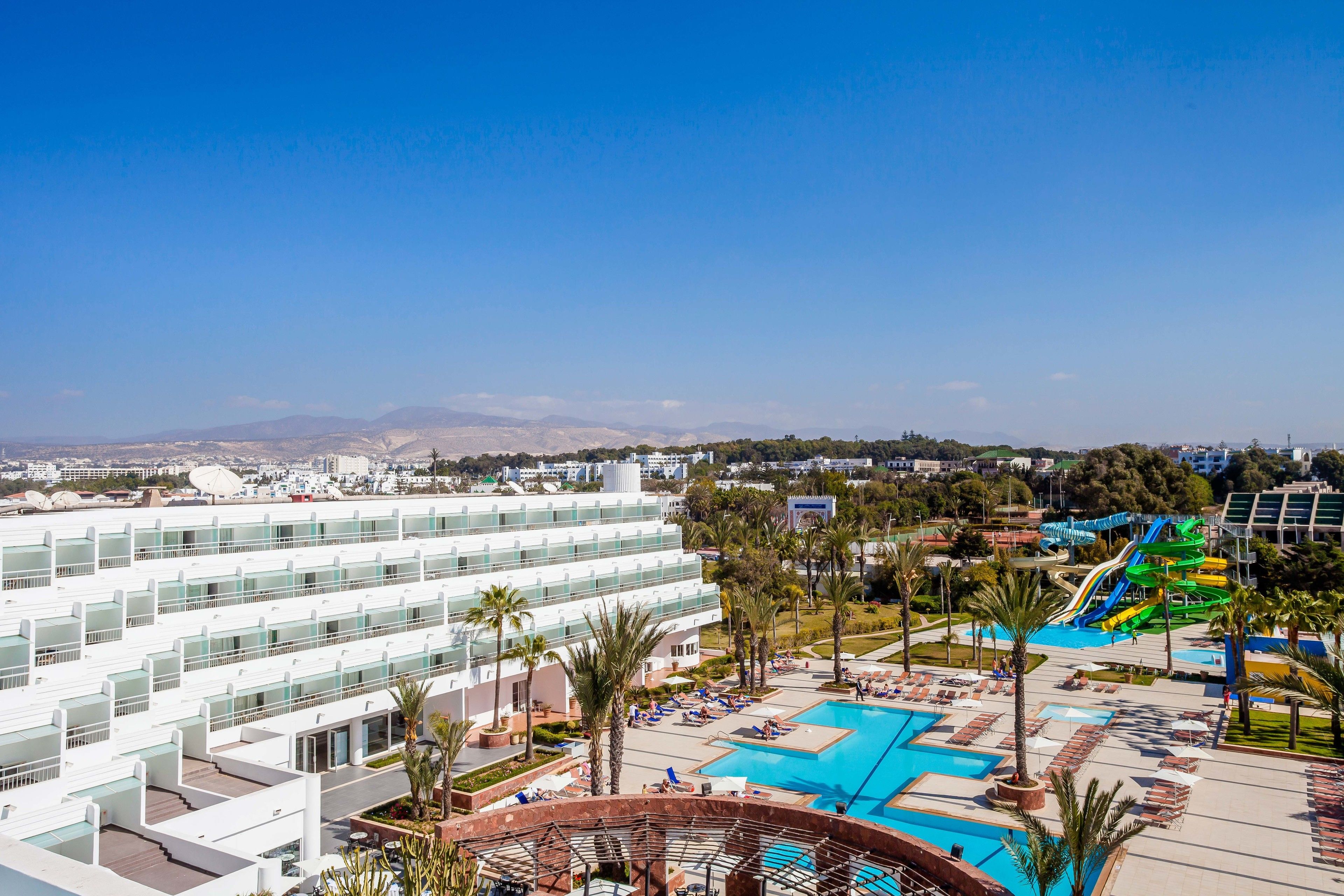 Een resort met diverse zwembaden, een waterpark en een modern hotelgebouw met tal van balkons.