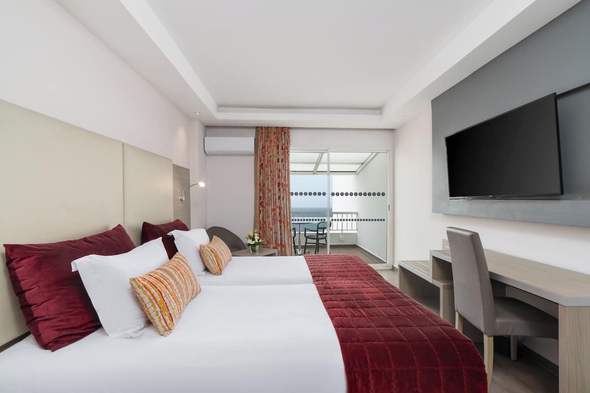 A modern hotel room with a large bed, a desk, and a TV.