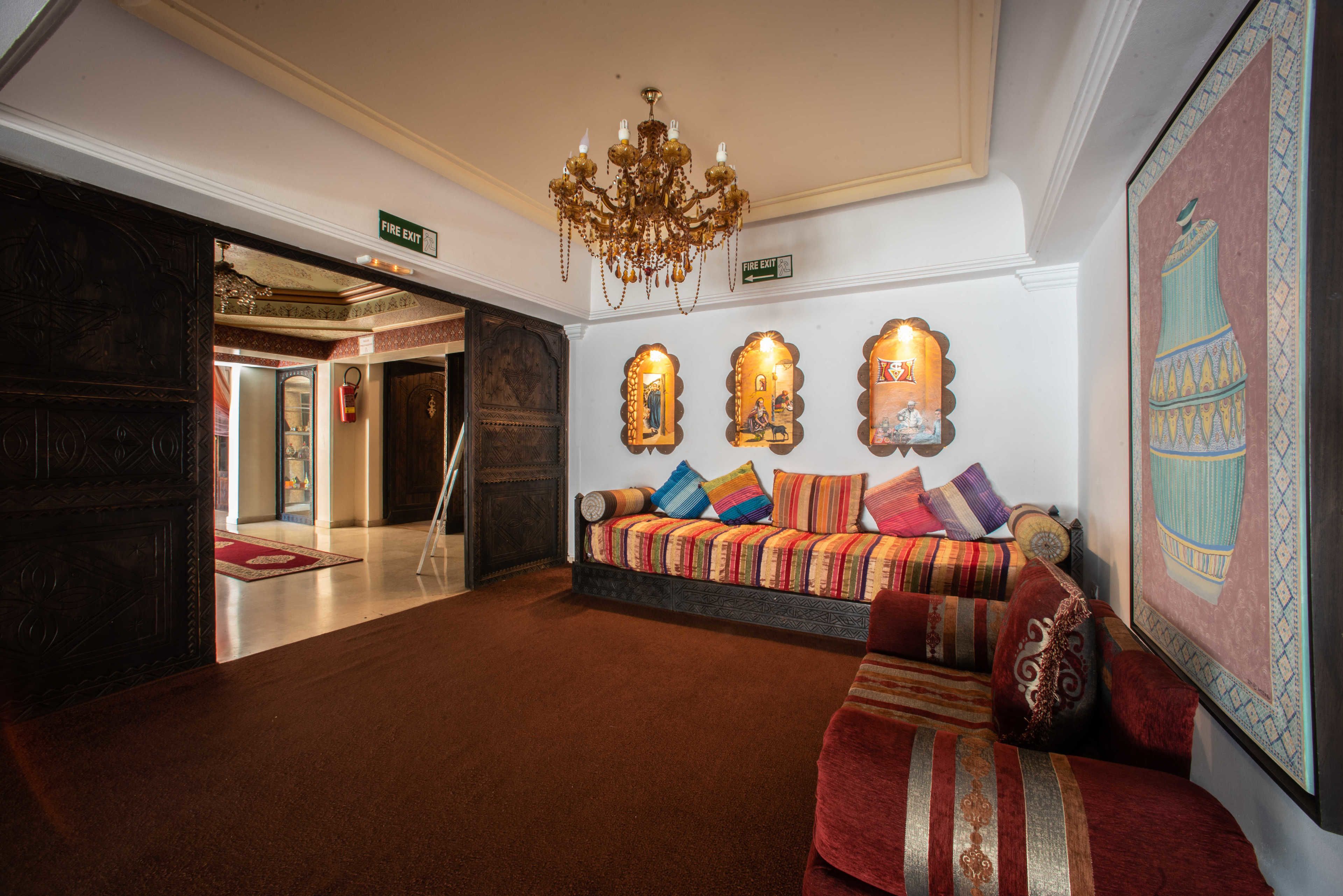 A lobby with a sofa set, a chandelier, and a large framed artwork.