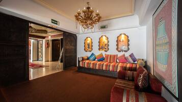 A lobby with a sofa set, a chandelier, and a large framed artwork.